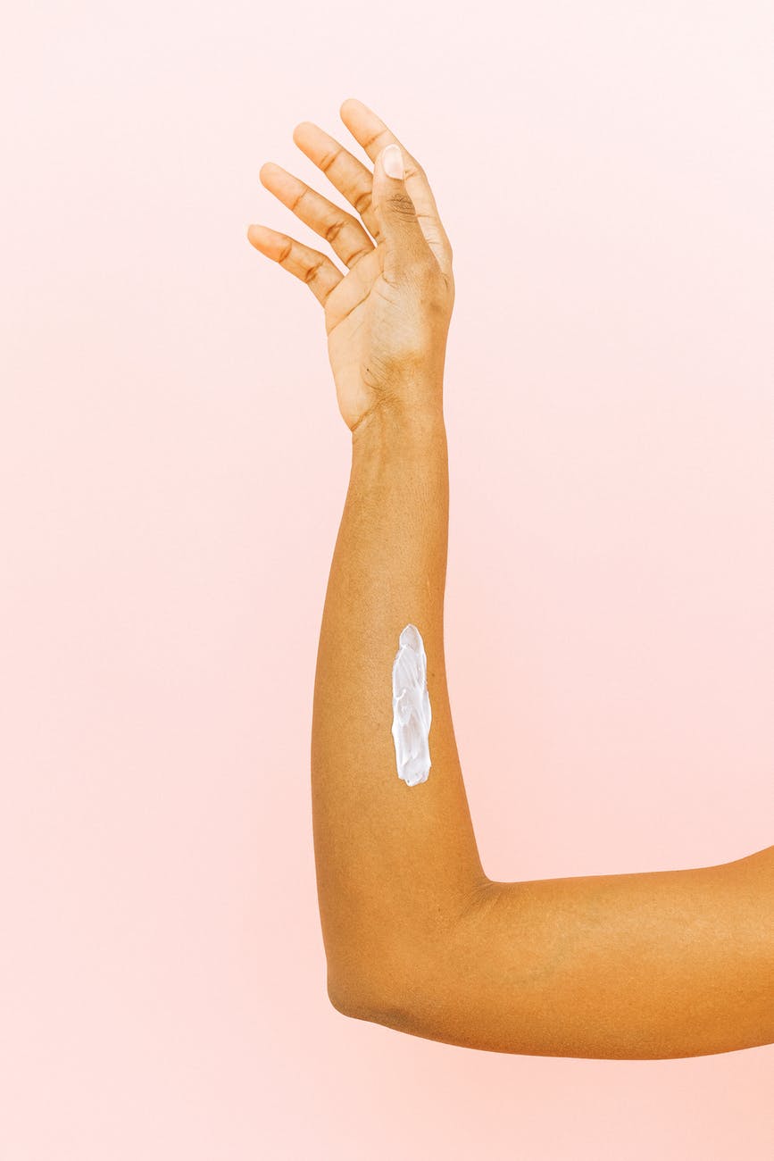 female arm with smear for skin care against pink background