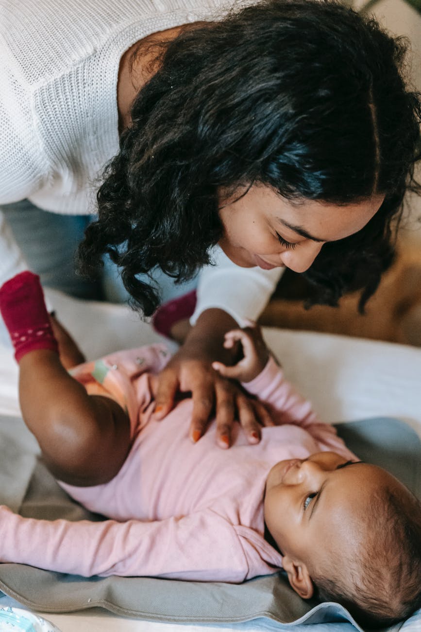 black mother putting clothes on baby, regalos para mamá