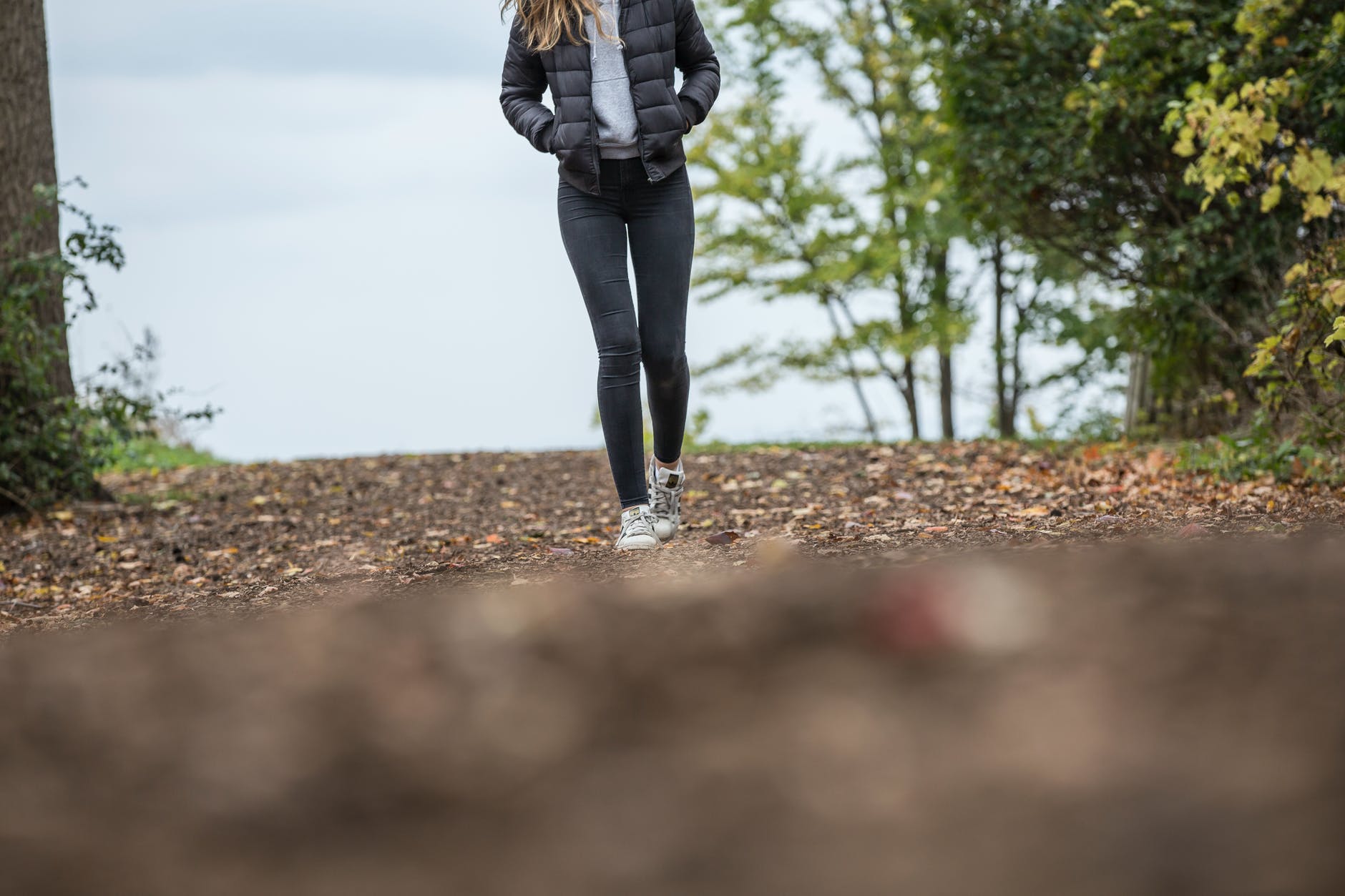 woman in black leggings while walking on brown road