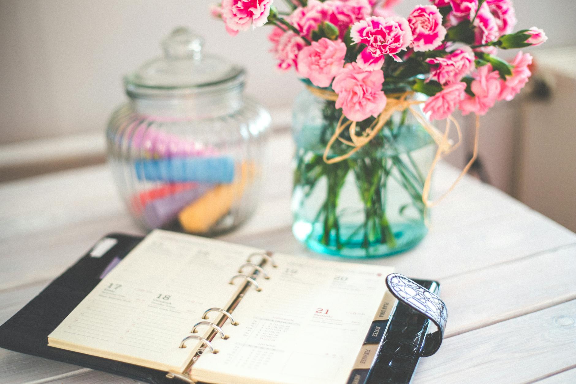 personal organizer and pink flowers on desk