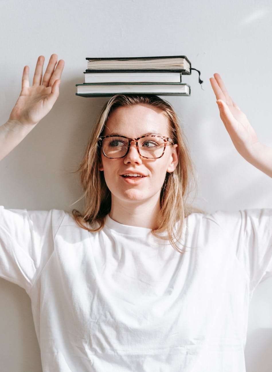 carefree student with heap of books on head